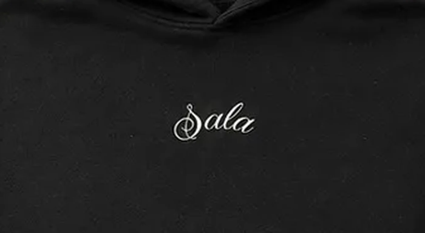 Chest embroidery detail — the Sala script in white thread